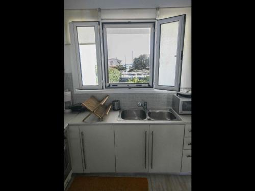 a kitchen with a sink and two windows at Pipina's Beach Apartment in Fanari