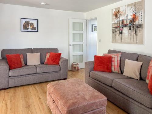 ein Wohnzimmer mit zwei grauen Sofas und roten Kissen in der Unterkunft Townend Cottage in Aikton