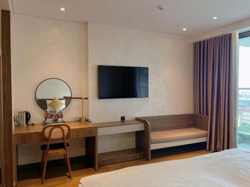 a hotel room with a desk and a television at Yang Apec Mandala Home in Phước Hậu