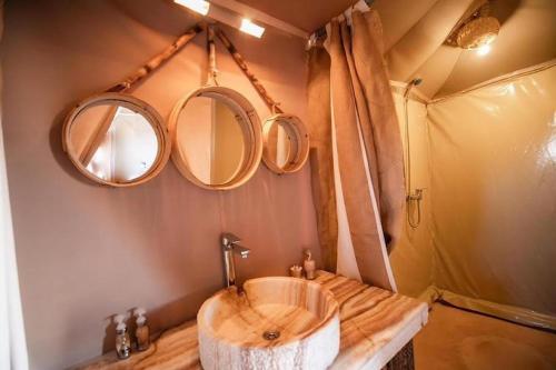a bathroom with a wooden sink and two mirrors at Merzouga Glossy Camp in Merzouga
