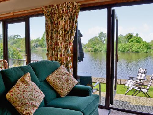a living room with a couch and a view of a lake at Heron's View - 28279 in Brundall