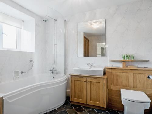 a bathroom with a tub and a toilet and a sink at The Mains in Keldhead