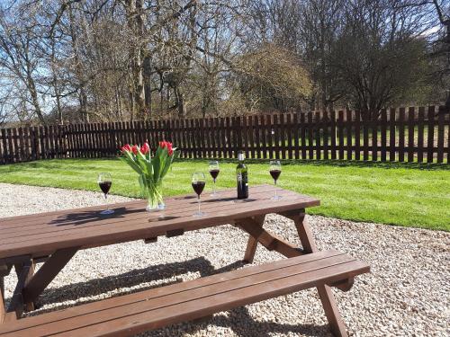 a wooden picnic table with wine glasses and flowers on it at Eagles Gate Lodge in Banff