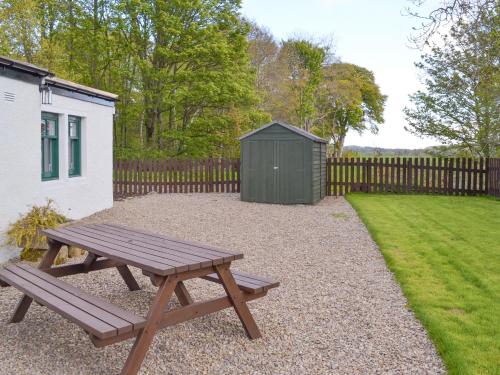 a wooden picnic table in a backyard with a fence at Eagles Gate Lodge in Banff