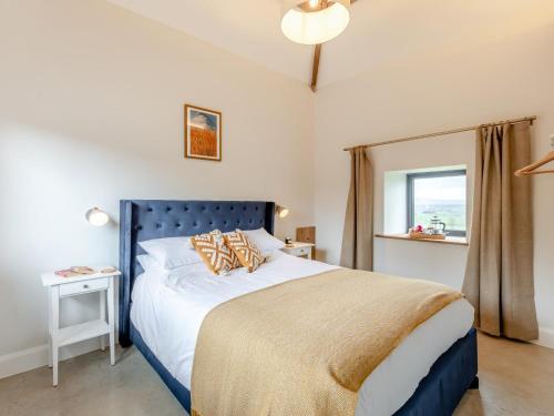 a bedroom with a bed with a blue headboard and a window at 2 Bed in Collington 91816 in Edwin Loach