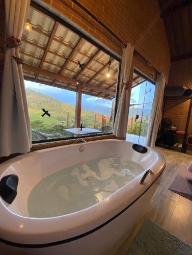 a large bath tub in a room with a large window at REFUGIO PIEMONTE Chalés in Socorro