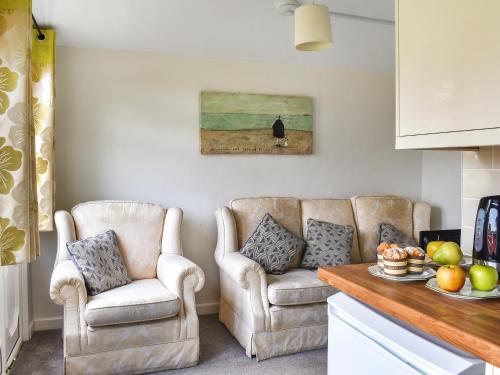 ein Wohnzimmer mit zwei Stühlen und einem Tisch in der Unterkunft Trevose Head - Uk47556 in Saint Merryn