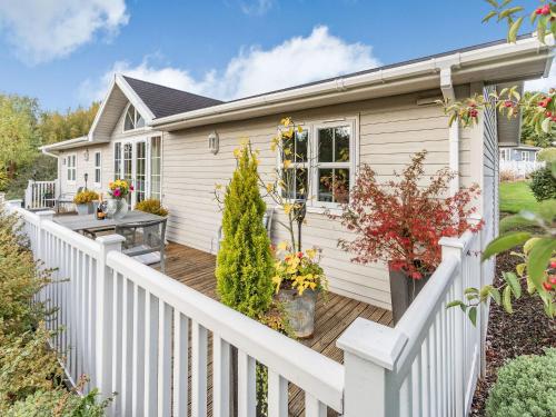a house with a white fence and a wooden deck at Beech Tree Lodge in Willington