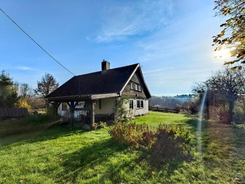 an old house on a grassy field in front at Na Żurawim Wzgórzu in Pasym