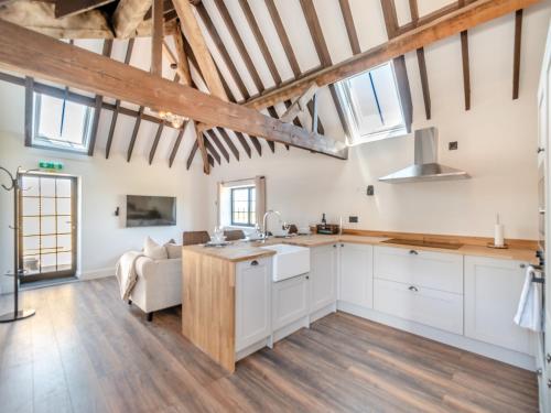 a kitchen with white cabinets and wooden floors and windows at Corley Rocks Barn - Uk45939 in Corley