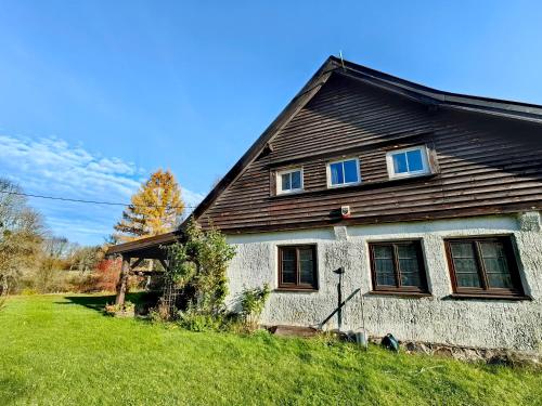 a house with a wooden roof on a green yard at Na Żurawim Wzgórzu in Pasym