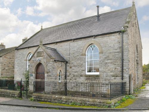 an old brick church with a fence at The Old Chapel in Aysgarth