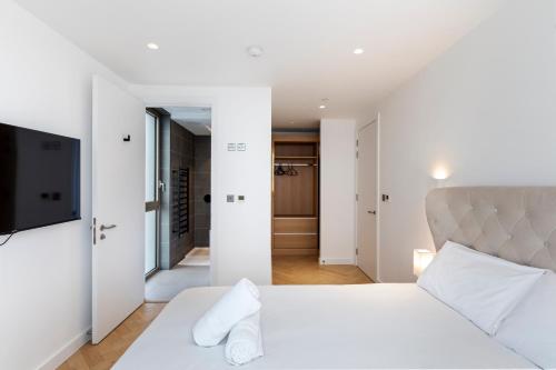 een slaapkamer met een wit bed en een flatscreen-tv bij Stylish Flat-Leisure Pool & Gym in Londen