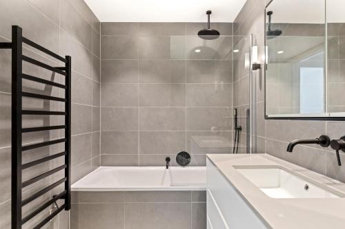 een badkamer met een ligbad en een wastafel bij Stylish Flat-Leisure Pool & Gym in Londen