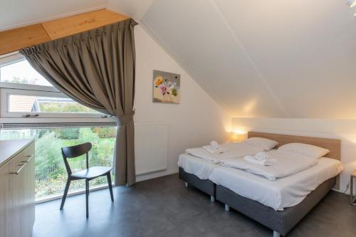 a bedroom with a bed and a chair and a window at Zonnedorp 22 Vakantiehuis Anoes Renesse | Strandnabij Comfort in Zeeland in Renesse