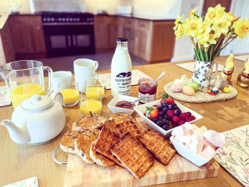 a table with a breakfast of bread and fruit and juice at Llwyn Ysgaw in Cemaes Bay