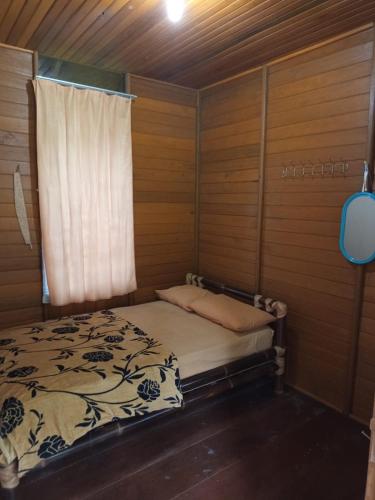 a bed in a wooden room with a window at Villa Kayu Danke in Ciguntur