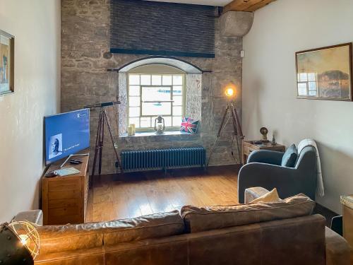 a living room with a couch and a tv at The Sail Loft - Royal William Yard in Millbrook