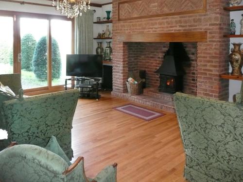 een woonkamer met een stenen open haard en 2 stoelen bij Dove Cote House in Westleigh