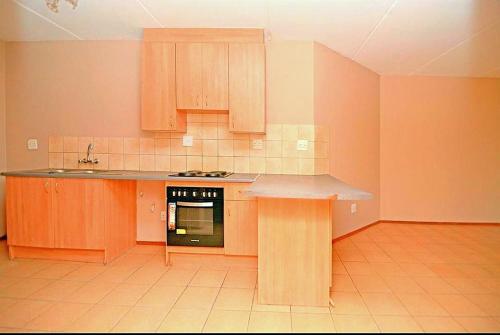 a kitchen with wooden cabinets and a counter top at M Gold Apartments in Pretoria