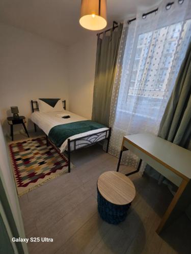 a bedroom with a bed and a table and a window at Green &White Cozy 3-Bedroom in London