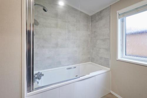 a white bath tub in a bathroom with a window at Sandy Lane 20 in York