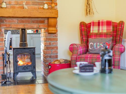 a living room with a fireplace and a chair and a table at Cowslip Cottage in Swarland