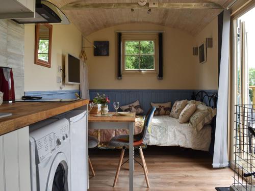 a kitchen and living room with a bed and a table at The Shepherd's Hut in Herstmonceux