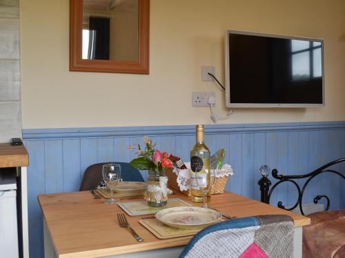 a dining room table with a bottle of wine on it at The Shepherd's Hut in Herstmonceux