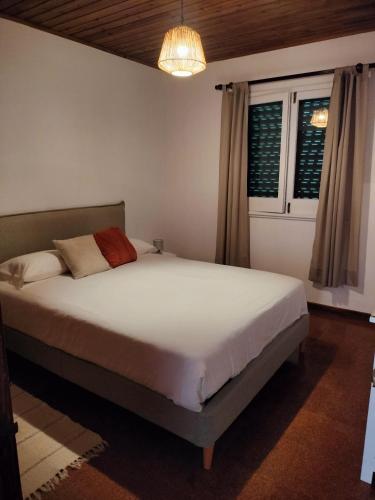 a bedroom with a bed and a chandelier at Casa das Pedras do Galego - Furnas in Furnas