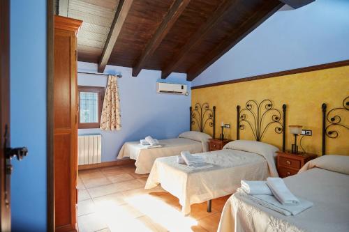 a room with three beds and a blue wall at Fuente Los Avellanos in Villanueva del Arzobispo