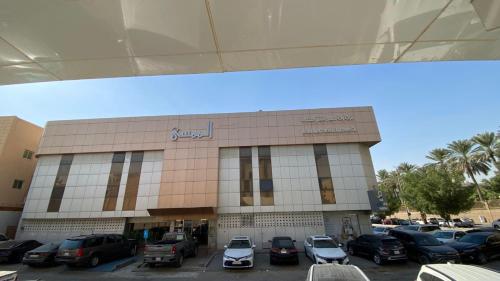 een gebouw met auto's geparkeerd op een parkeerplaats bij واحة الممسى للشقق المخدومة - اقتصادي in Riyad