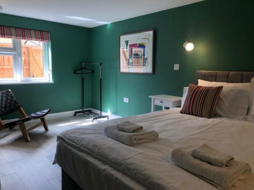 een slaapkamer met een groot bed met groene muren bij Perfitt Place in Bungay