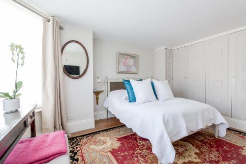a white bedroom with a bed and a mirror at Cresswell Lodge in Richmond