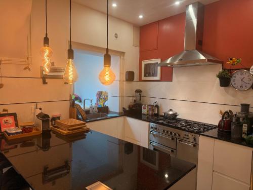 La cuisine est équipée de placards rouges et d'un four avec plaques de cuisson. dans l'établissement Maison Marie Charme & confort à Rouen centre, à Rouen