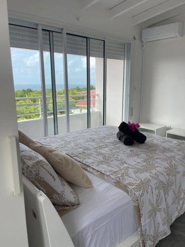 a bedroom with a white bed and a balcony at Villa Bel'Horizon in Capesterre
