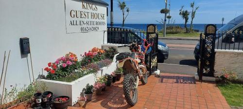 a motorcycle parked in front of a building with flowers at Kings' House in Douglas