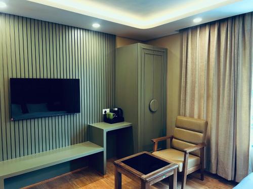 a hotel room with a chair and a television at Mountain Nest A Boutique Stay Near Dal Lake, Srinagar in Srinagar