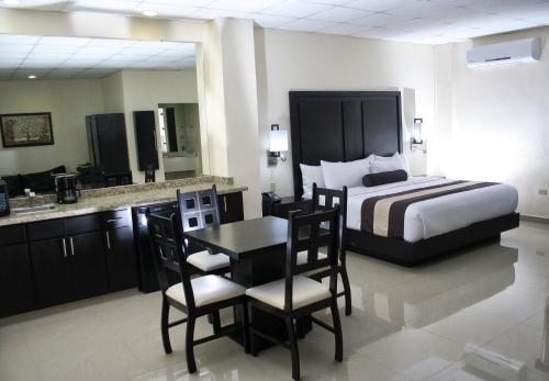 a hotel room with a bed and a table and chairs at Hotel El Camino Inn & Suites in Reynosa