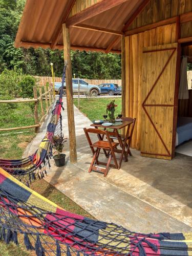 a hammock on a patio with a table and a barn at Pousada O Bosque in Joanópolis