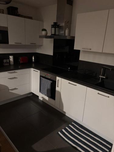 a kitchen with white cabinets and a stove top oven at Loft chaleureux avec wifi et terasse in Ceyrat