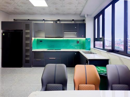 a kitchen with black and green cabinets and chairs at 阮黄酒店 in Hòa Ðình