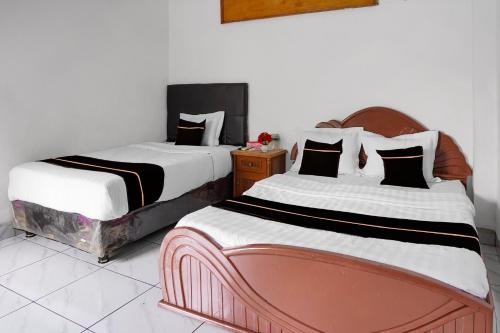 two beds sitting next to each other in a room at Collection O near Universitas Negeri Padang formerly Hotel Amra in Padang