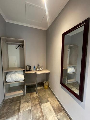 a room with a mirror and a desk with a bed at The Hornbill Lodge in Nata