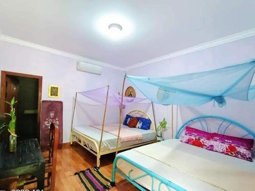 een slaapkamer met twee bedden en een blauwe luifel bij Phonluer Angkor Homestay, in Siem Reap