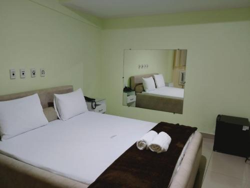 a hotel room with two beds and a mirror at Hotel Aliança in Salvador