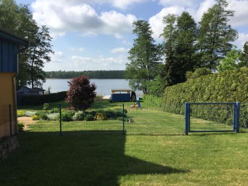 a fence in a yard with a lake in the background at Am Blauen See in Dabel