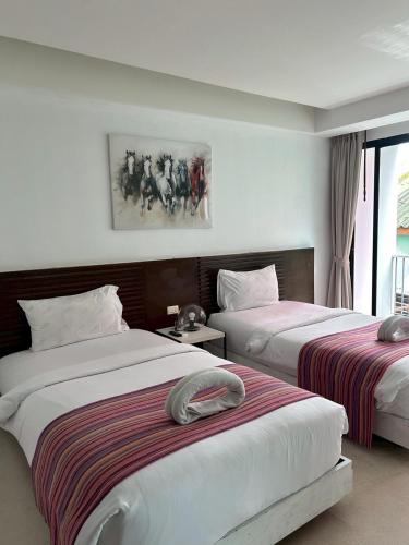 a bedroom with two beds and a painting on the wall at Coco boutique hotel in Patong Beach
