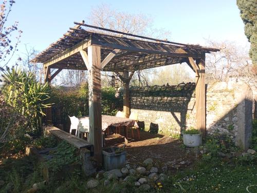 een houten pergola met een kat eronder bij Maison de maître in Bernac-Debat