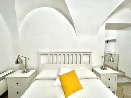 a white bedroom with a bed with a yellow pillow at Sardinian Gallery Corso in Bosa